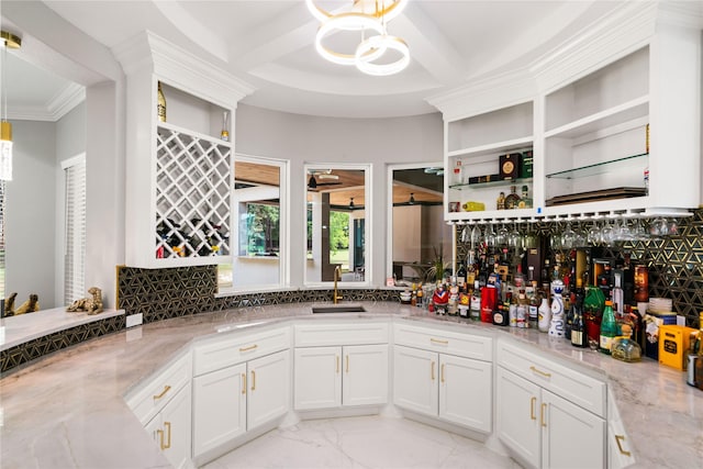 kitchen featuring hanging light fixtures, white cabinetry, sink, and light stone counters