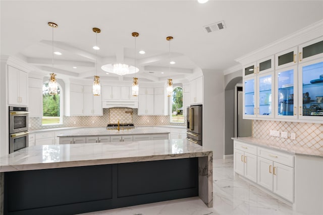 kitchen with white cabinetry, decorative light fixtures, stainless steel appliances, and a large island with sink