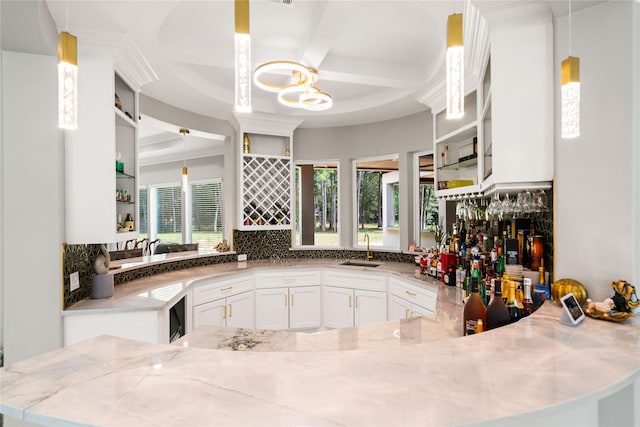 bar featuring tasteful backsplash, sink, pendant lighting, and white cabinets