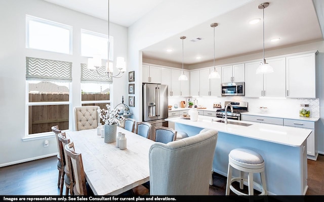 kitchen featuring decorative light fixtures, white cabinets, and appliances with stainless steel finishes