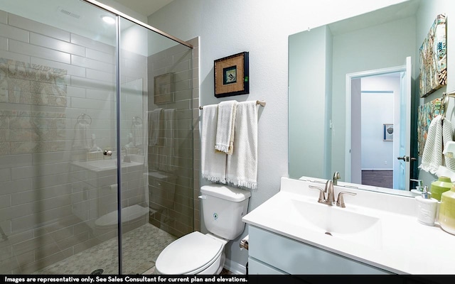 bathroom with vanity, a shower with shower door, and toilet