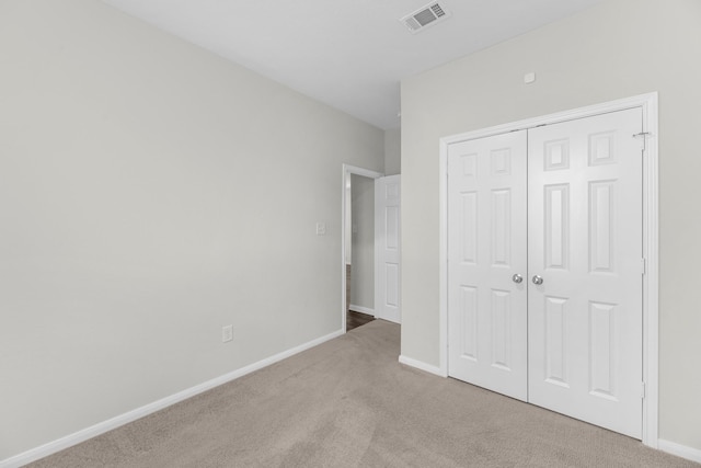 unfurnished bedroom with light colored carpet and a closet