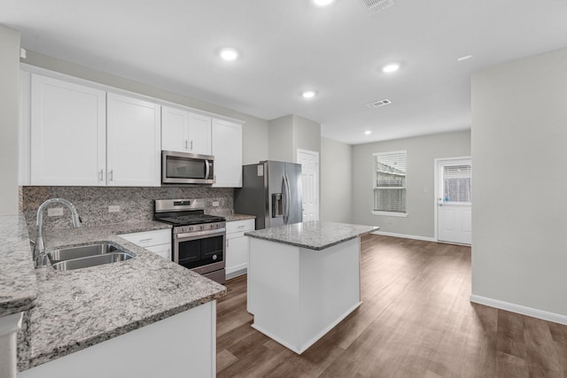 kitchen featuring stainless steel appliances, a center island, sink, and white cabinets