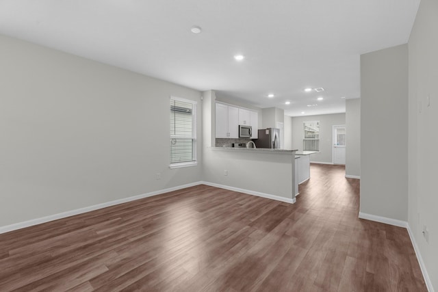 kitchen with white cabinetry, plenty of natural light, kitchen peninsula, and appliances with stainless steel finishes