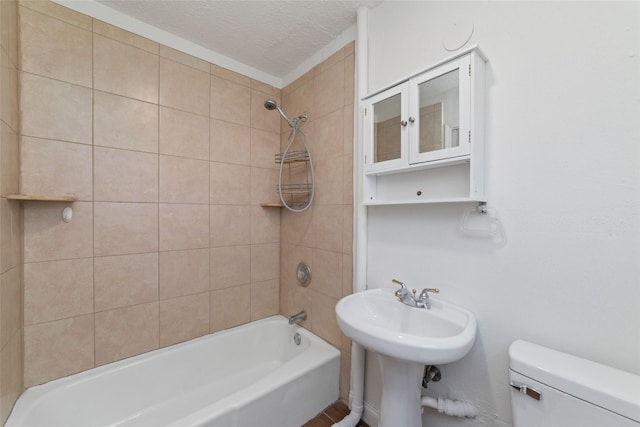 bathroom featuring tiled shower / bath combo, toilet, and a textured ceiling