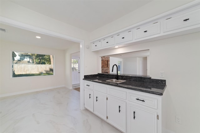 kitchen with white cabinetry, dark stone counters, and sink