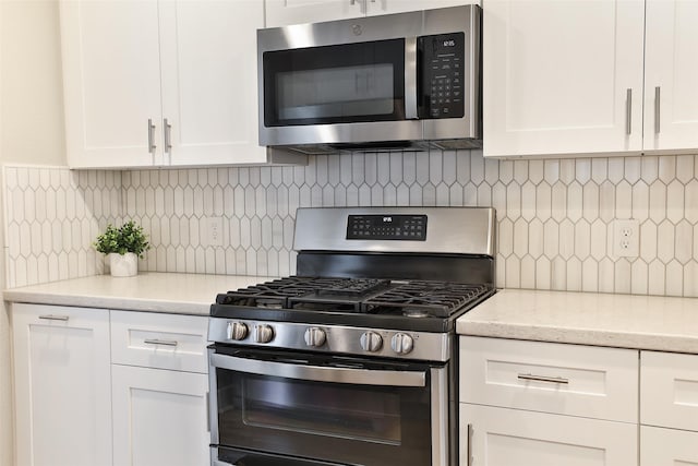 kitchen with white cabinetry, light stone countertops, decorative backsplash, and stainless steel appliances