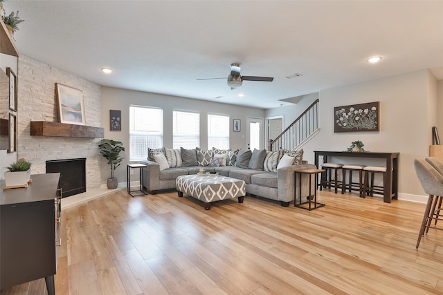 living room featuring a fireplace, light hardwood / wood-style flooring, and ceiling fan