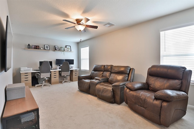 interior space with a textured ceiling, light colored carpet, and ceiling fan