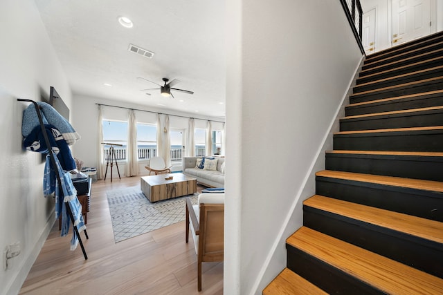 stairway with ceiling fan and hardwood / wood-style floors