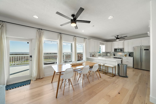 dining space with sink, light hardwood / wood-style floors, and a textured ceiling