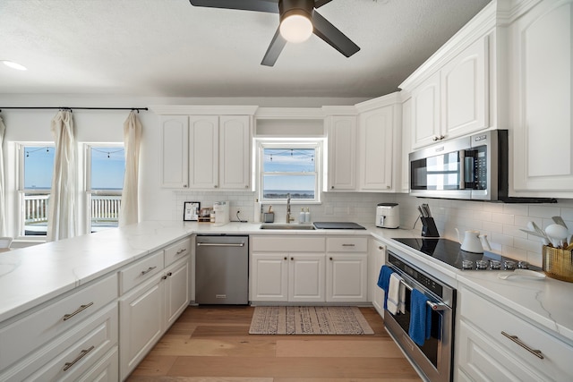 kitchen with sink, light hardwood / wood-style flooring, white cabinetry, stainless steel appliances, and tasteful backsplash