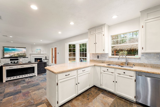 kitchen with sink, white cabinetry, tasteful backsplash, stainless steel dishwasher, and kitchen peninsula