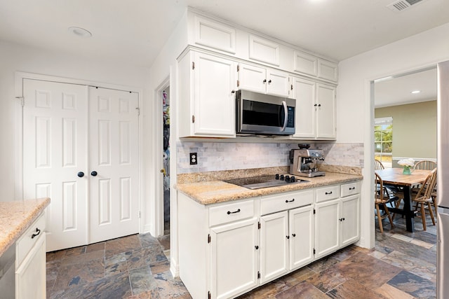 kitchen featuring black electric cooktop, backsplash, and white cabinets