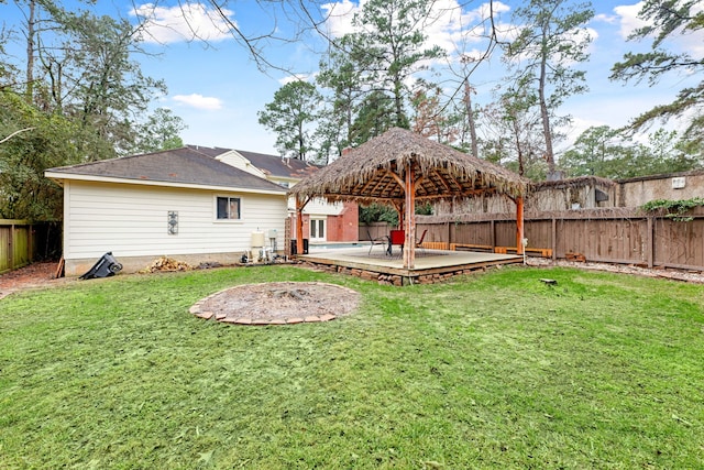 rear view of house featuring a wooden deck, a gazebo, and a lawn