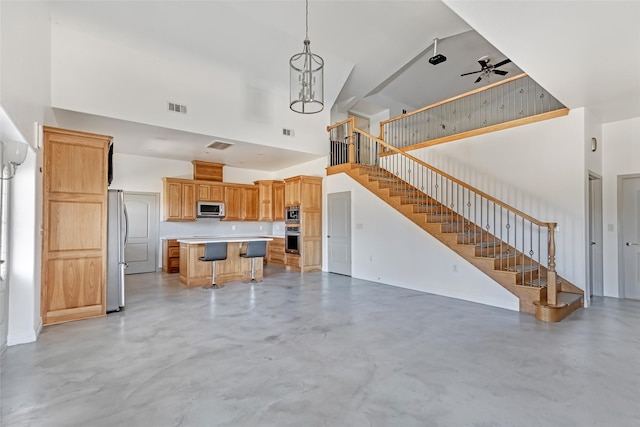 unfurnished living room with a high ceiling and ceiling fan