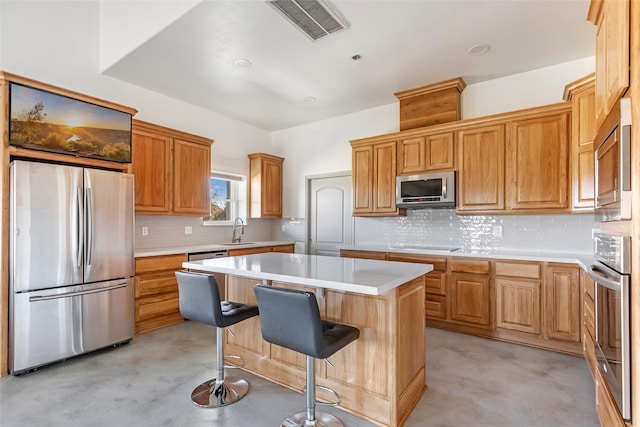 kitchen with appliances with stainless steel finishes, a breakfast bar, sink, decorative backsplash, and a center island