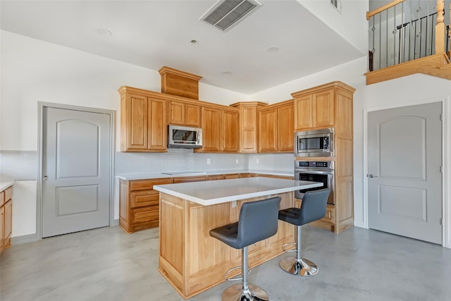 kitchen featuring a kitchen island, tasteful backsplash, appliances with stainless steel finishes, and a breakfast bar