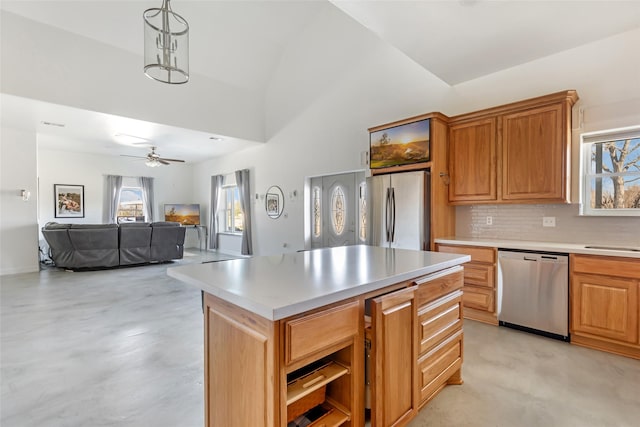 kitchen featuring lofted ceiling, a center island, hanging light fixtures, appliances with stainless steel finishes, and backsplash