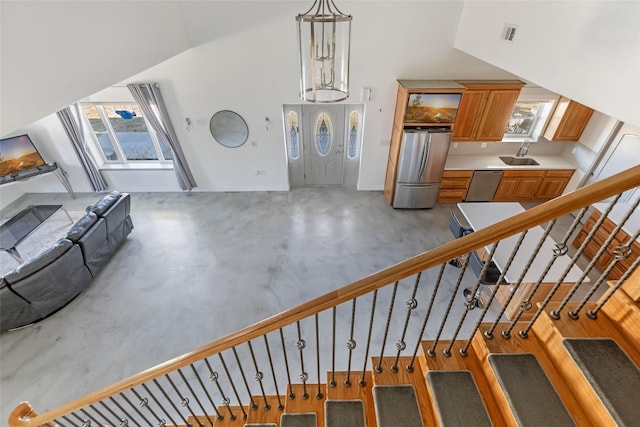 staircase with concrete flooring, sink, and high vaulted ceiling