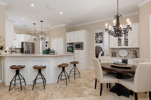 kitchen with pendant lighting, stainless steel appliances, white cabinets, and a kitchen bar