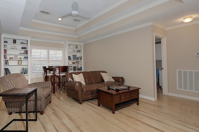 living room featuring ornamental molding, light hardwood / wood-style floors, a raised ceiling, and ceiling fan