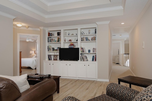 living room with crown molding, a raised ceiling, and light wood-type flooring