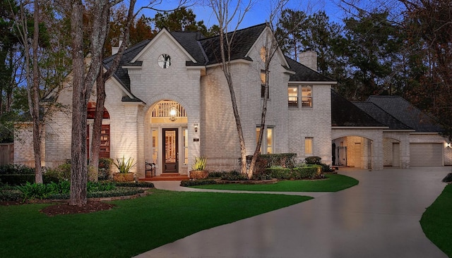 french provincial home with a garage and a front yard