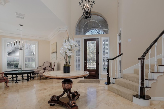 entryway with a notable chandelier, ornamental molding, and a high ceiling