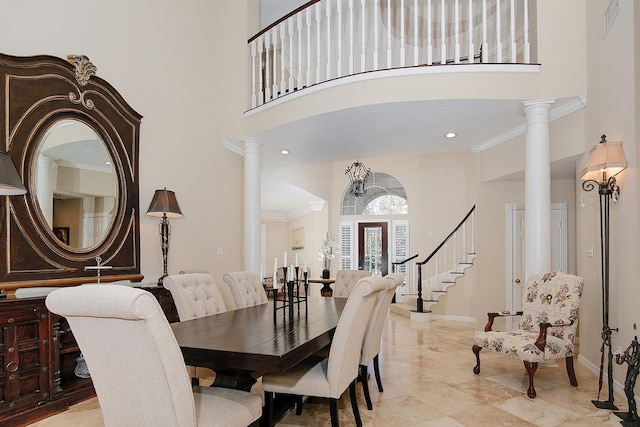 dining space with a towering ceiling, ornamental molding, and decorative columns