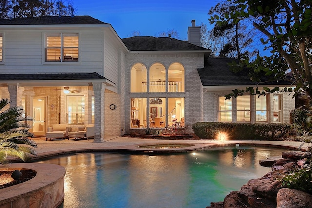 rear view of property with a balcony, outdoor lounge area, a pool with hot tub, and a patio