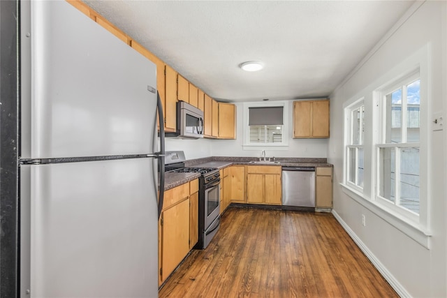 kitchen with appliances with stainless steel finishes, sink, light brown cabinets, and dark hardwood / wood-style flooring