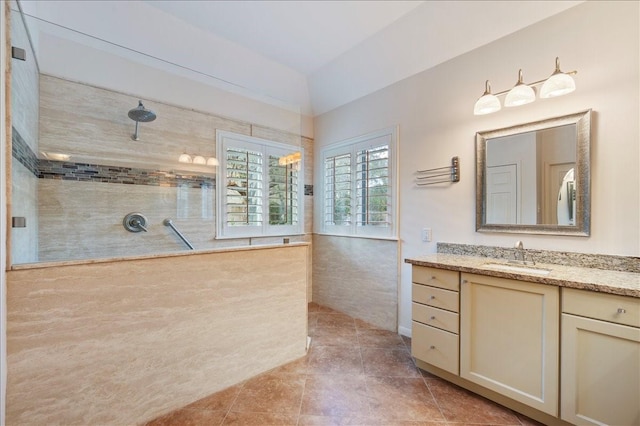 bathroom with vanity, tile patterned flooring, lofted ceiling, and tiled shower