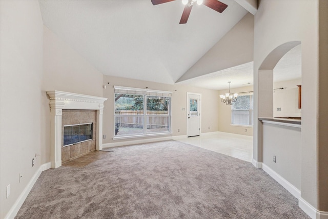 unfurnished living room featuring high vaulted ceiling, a fireplace, light colored carpet, and plenty of natural light