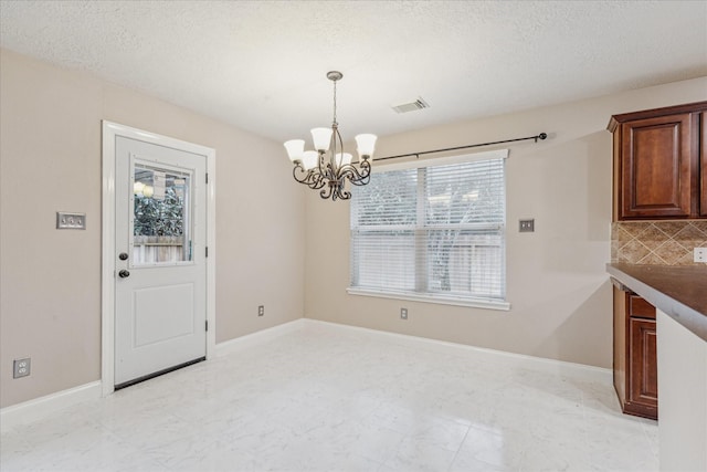 unfurnished dining area with an inviting chandelier and a textured ceiling