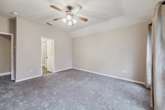 unfurnished bedroom with ceiling fan, vaulted ceiling, a textured ceiling, and dark colored carpet