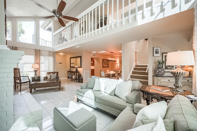 living room featuring ceiling fan, light tile patterned floors, a textured ceiling, and a high ceiling