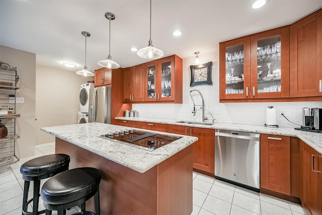 kitchen with light tile patterned floors, sink, appliances with stainless steel finishes, light stone counters, and stacked washer / drying machine