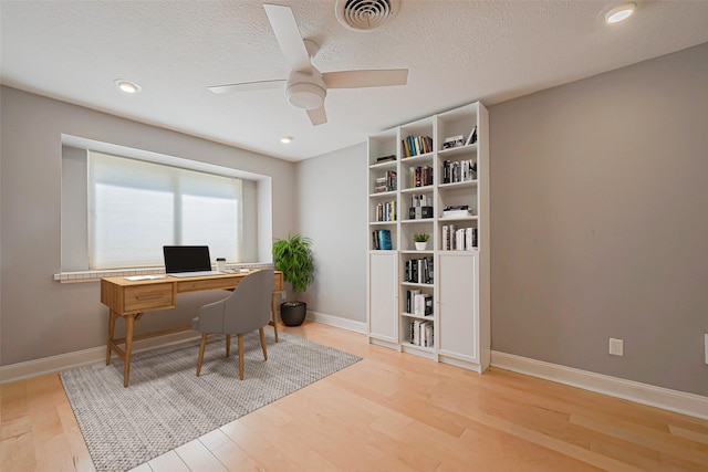 home office with ceiling fan, a textured ceiling, and light wood-type flooring