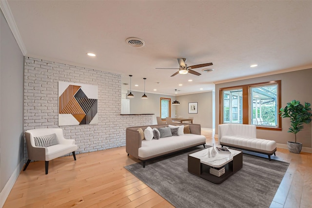 living room with crown molding, brick wall, plenty of natural light, and light hardwood / wood-style floors