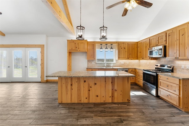 kitchen featuring sink, appliances with stainless steel finishes, a center island, light stone countertops, and decorative light fixtures