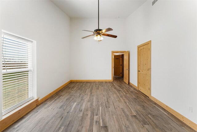 spare room with hardwood / wood-style flooring, a towering ceiling, and ceiling fan