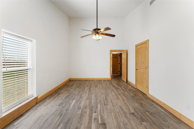 unfurnished room with ceiling fan, a high ceiling, and wood-type flooring