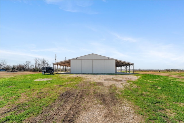 view of outbuilding featuring a rural view and a lawn