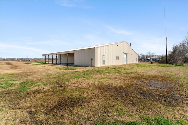 back of property featuring an outdoor structure and a lawn