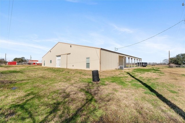 view of side of home featuring central AC, an outdoor structure, and a lawn