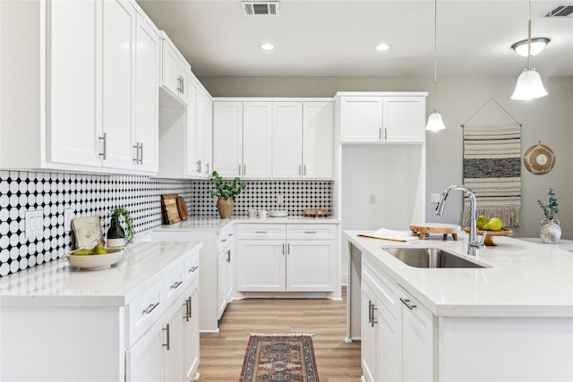 kitchen featuring pendant lighting, sink, white cabinetry, and light hardwood / wood-style floors