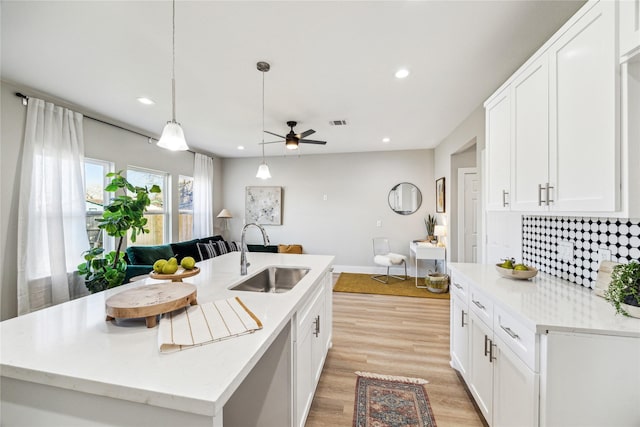 kitchen with white cabinets, sink, and a kitchen island with sink