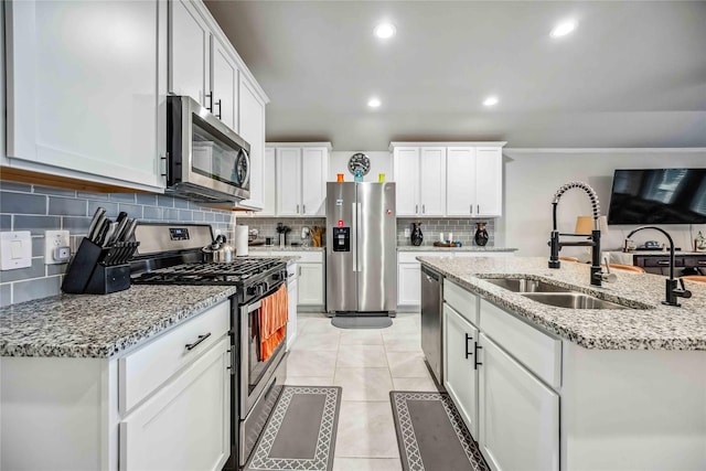 kitchen featuring sink, light tile patterned floors, appliances with stainless steel finishes, white cabinetry, and light stone counters