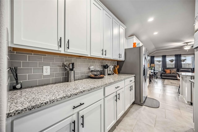 kitchen featuring light stone counters, light tile patterned floors, decorative backsplash, and white cabinets